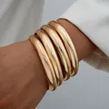 Five-piece set of polished gold-finished wide metal bangles shown on a female wrist - Gold Chunky Style (6546701HB)