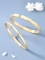 Dettaglio macro di bracciali in acciaio al titanio dorato con numeri romani incisi lucidi - Stile Stretto / Oro