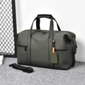 Olive green travel duffel bag in matte waterproof fabric with orange luggage tag detail - Green