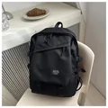 Detail view of large black canvas backpack with multi-layer zippers on a beige chair - Black