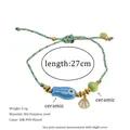 Detail showing blue ceramic fish and shell charms on a green braided 18K PVD gold bracelet - Blue Fish Style (MSB0477)