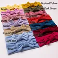 Flat lay of 14 colorful elastic baby headbands with large handmade soft cotton bows - 14 Colors Mixed