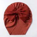 Détail d'un turban bébé avec grand nœud en maille côtelée couleur terre cuite - Bordeaux