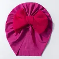 Détail d'un turban bébé avec grand nœud rouge et tissu côtelé extensible rose vif - Fuchsia