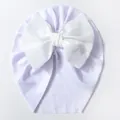 Detail einer helllilafarbenen Baby-Strickmütze mit großer weißer Zierschleife - Weiß