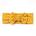 Close-up of mustard yellow knitted baby headband with a large decorative bow tie knot - Khaki/Earth Yellow