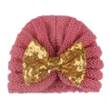 Détail d'un bonnet en tricot rose pour bébé orné d'un grand nœud en paillettes dorées - Rose Poudré