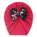 Detail der Baby-Mütze mit großer dunkelblauer Blumen-Schleife auf dunkelrosa Stoff - Fuchsia