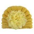 Detailaufnahme einer Baby-Strickmütze mit großer Chiffonblume und goldenem Punktdruck - Erdgelb