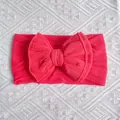 Coral pink baby nylon headband featuring a large knitted double twist bow detail - Red