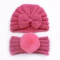 Detail of bright pink knitted baby hat with bow and headband with large pom-pom - Rose Red