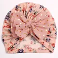 Detailed close-up of baby turban hat with floral print and large gold polka dot bow - Snow Bud + Dusty Pink