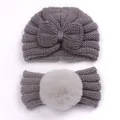 Detail view of grey knit baby turban hat with bow and matching faux fur pompom headband - Gray