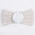 Detail of a creamy white knitted baby headband featuring a soft layered fabric flower - Beige