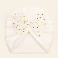 Detail of white baby beanie with a large gold polka dot mesh bow decoration - White