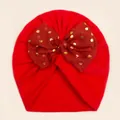 Close-up of red knit baby hat with large gold polka dot tulle bow detail - Red