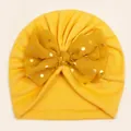 Detail of baby turban hat showing ginger yellow knit fabric and golden dot mesh bow - Yellow