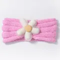 Close-up of pink knitted baby headband with a decorative white fabric flower - Pink