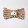 Detail of baby knitted headband featuring a cute cartoon lion patch on khaki wool fabric - Coffee