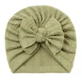 Gros plan détaillé du bonnet turban tricoté vert sauge pour bébé avec un grand nœud - Vert