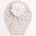 Detail of baby striped turban hat featuring a large white mesh flower with gold polka dots - White