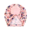 Détail d'un bonnet turban rose à fleurs pour bébé avec un grand pompon en peluche - Rose