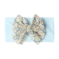 Détail d'un bandeau doux pour bébé avec un ruban bleu clair et un grand nœud marguerite - Bleu