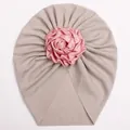 Macro detail of ribbed knit infant turban hat featuring a large pink satin rose flower decoration - Gray