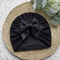Détail du bonnet turban noir pour bébé avec grand nœud posé sur une natte tissée - Taille unique / Noir