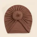 Detail van baby donut muts in koffiebruin met zachte geplooide gebreide stofstructuur - koffiekleur