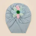 Detail of baby turban hat showing light blue ribbed knit fabric and colorful cloth flower - Blue