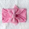 Detail van roze zachte nylon baby hoofdband met een gelaagde getextureerde strik - Roze