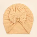 Macro detail of soft waffle knit texture and large bow on infants' turban hat - Beige