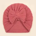 Detail of pink waffle knit baby beanie featuring a large soft bow and ribbed edge - Dark Mauve