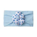 Detail of baby headband with a large blue polka dot fabric flower on soft fabric - Blue
