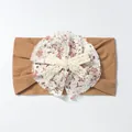Detail of baby headband with brown elastic fabric and floral white lace bow accessory - Coffee