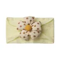 Detail of baby headband featuring a large 3D flower with brown polka dots on a yellow band - Beige