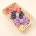 Three-pack waffle knit baby bow headbands in pink, grey, and purple in a basket - Dusty Rose, Gray, Purple