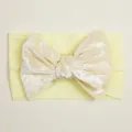 Détail d'un bandeau jaune en velours avec nœud papillon élastique pour bébé - Beige