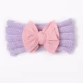 Detailaufnahme des gestrickten lila Baby-Stirnbands mit großer rosa Stoffschleife - Lila+Rosa