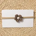 Detailed macro view of a soft brown knitted flower on a thin elastic baby headband - Brown Knitted Button Flower