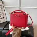 Chic red faux leather crossbody bag with top handle and gold logo in 2025 winter style - Red