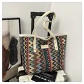 Detailaufnahme von buntem Wellenstrickgewebe und Leder-Logoetikett einer modischen Tasche - Weiß