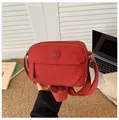 Dettaglio della borsa a tracolla in nylon rosso con tracolla larga e logo rotondo - Arancione