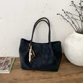 Gros plan d'un sac cabas noir mat avec pendentif en perles de bois et texture suédée - Avec Pendentif / Noir
