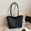 Detail of black lychee grain leather tote bag with embossed fashion text and long straps - Black