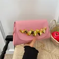 Pink patent leather clutch bag featuring a distinctive gold wavy handle and chain strap - Pink