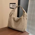 Dettaglio della borsa hobo kaki con tessuto testurizzato e ampia tracolla su legno - Cachi Chiaro