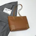 Detailed macro view of brown lychee-textured leather tote bag with reinforced stitching - Brown