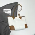 White faux leather tote bag with brown straps styled with a grey blazer and magazine - White